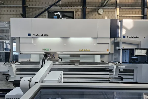 Die TruBend 5170 mit ToolMaster steht in einer Werkhalle; Steuerpult und Blechteile sind unter Neonlicht sichtbar.