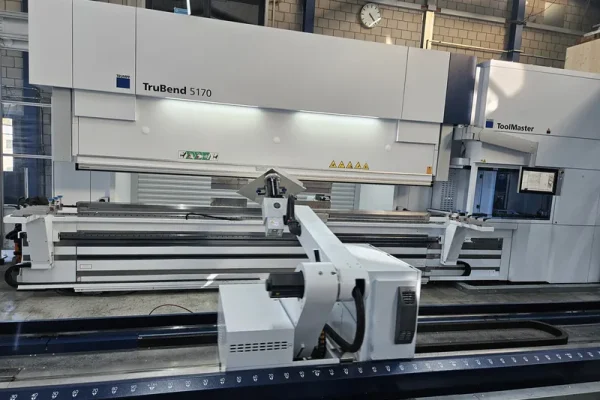Eine TruBend 5170 Abkantpresse steht in sauberer, heller Fabrik mit Blechteilen und Robotik für die Blechbearbeitung.