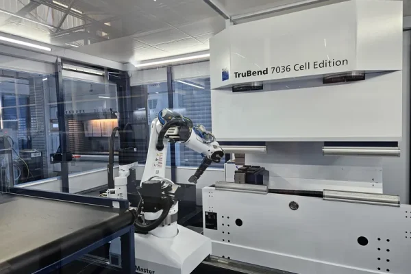 Ein Roboterarm arbeitet in einer verglasten Zelle neben einer TruBend 7036 Biegemaschine in moderner Blechbearbeitungsumgebung.