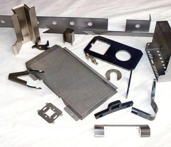 Verschiedene Blechbauteile, gelocht, gebogen und geschnitten, auf weißem Untergrund; Beispiele für Blechbearbeitungstechniken.