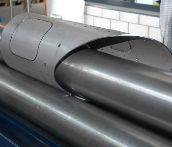 Ein Blech wird in einer Industrie-Blechbearbeitungsmaschine durch große Walzen gebogen und geformt.