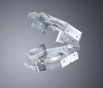Ein metallisches Maschinenteil mit kantigen, ineinandergreifenden Elementen und Zahnradstruktur vor grauem Hintergrund.