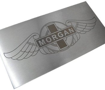 Metalltafel mit Morgan-Logo: gestanzte Flügel, runder Emblemkern mit Kreuz, MORGAN-Schriftzug mittig.