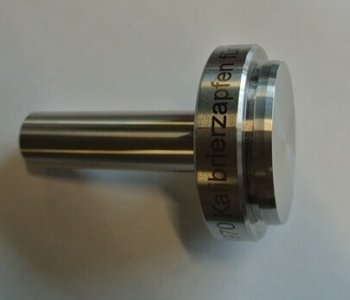 Zylindrisches Metallteil mit flachem Ende und Gravur am Rand, liegend auf heller Fläche, fachgerecht blechbearbeitet.