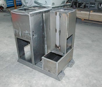 Metall-Maschinenrahmen mit zwei rechteckigen Fächern, Öffnungen, auf Betonboden in Werkstatt mit Blechbearbeitungsgeräten.