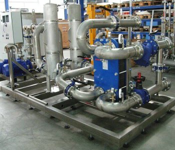 Verbundene Metallrohre, Ventile und blaue Pumpen auf Stahlrahmen in einer Fabrik für Blechbearbeitung montiert.